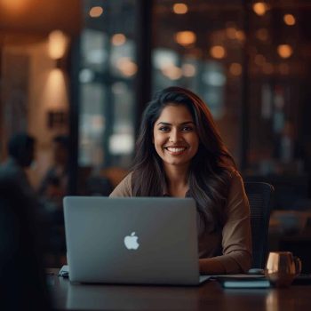 Friendly small business owner woman sitting at desk, laptop open, smiling, warm lighting, professional, modern office, no text